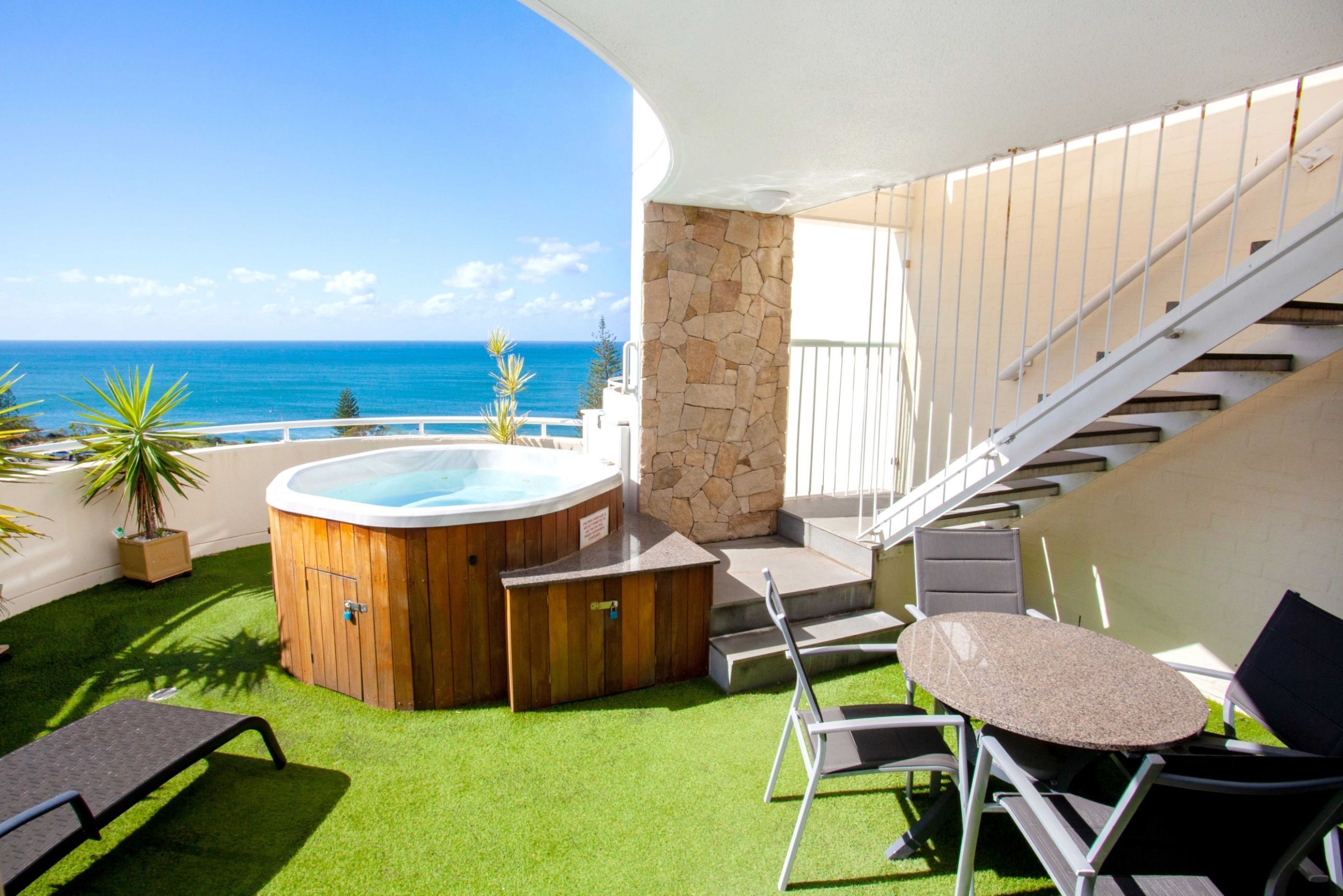 A rooftop terrace with a hot tub, outdoor seating, and a view of the ocean.
