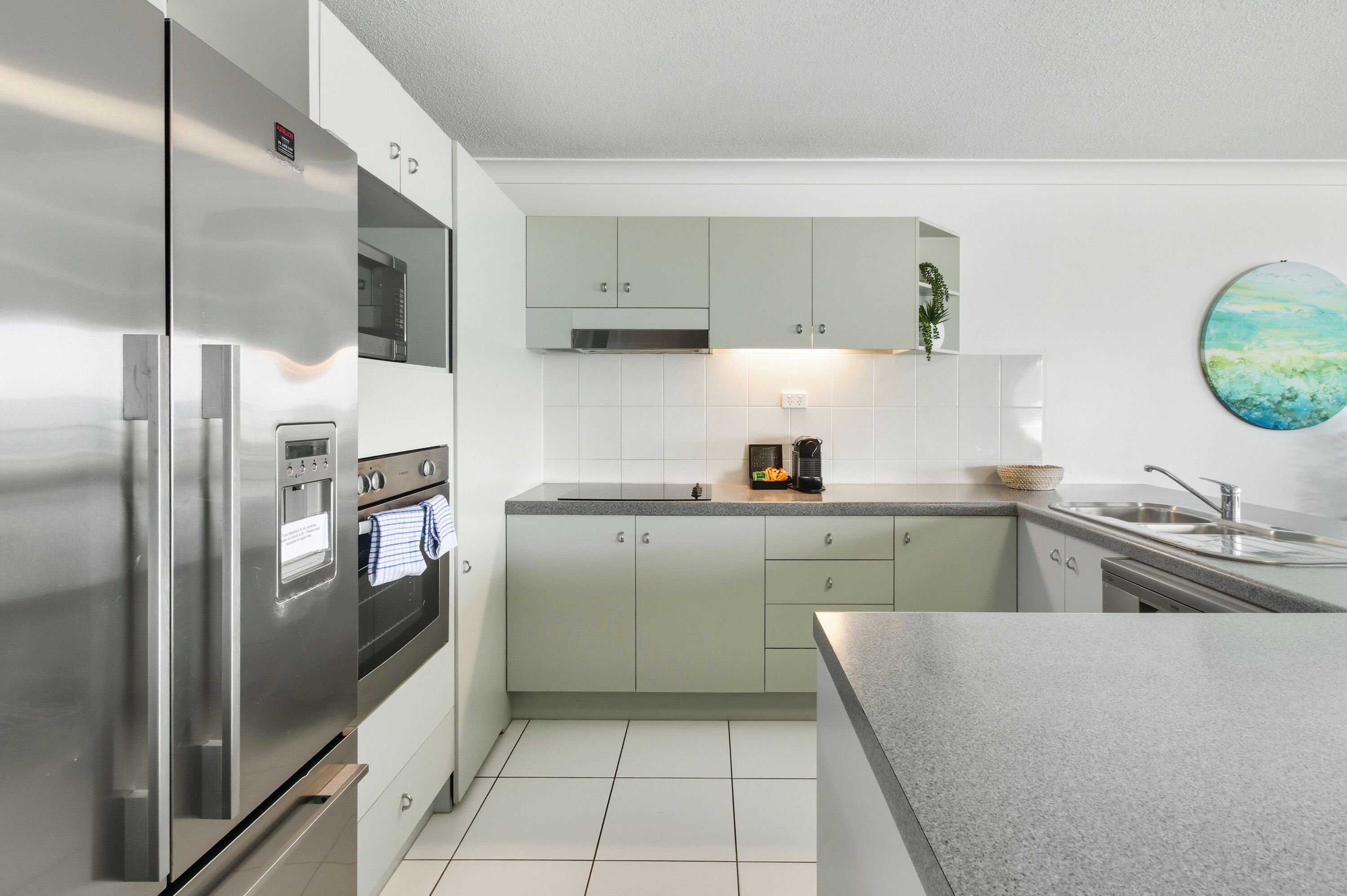 Una cocina moderna con refrigerador de acero inoxidable, horno empotrado y encimera de granito.