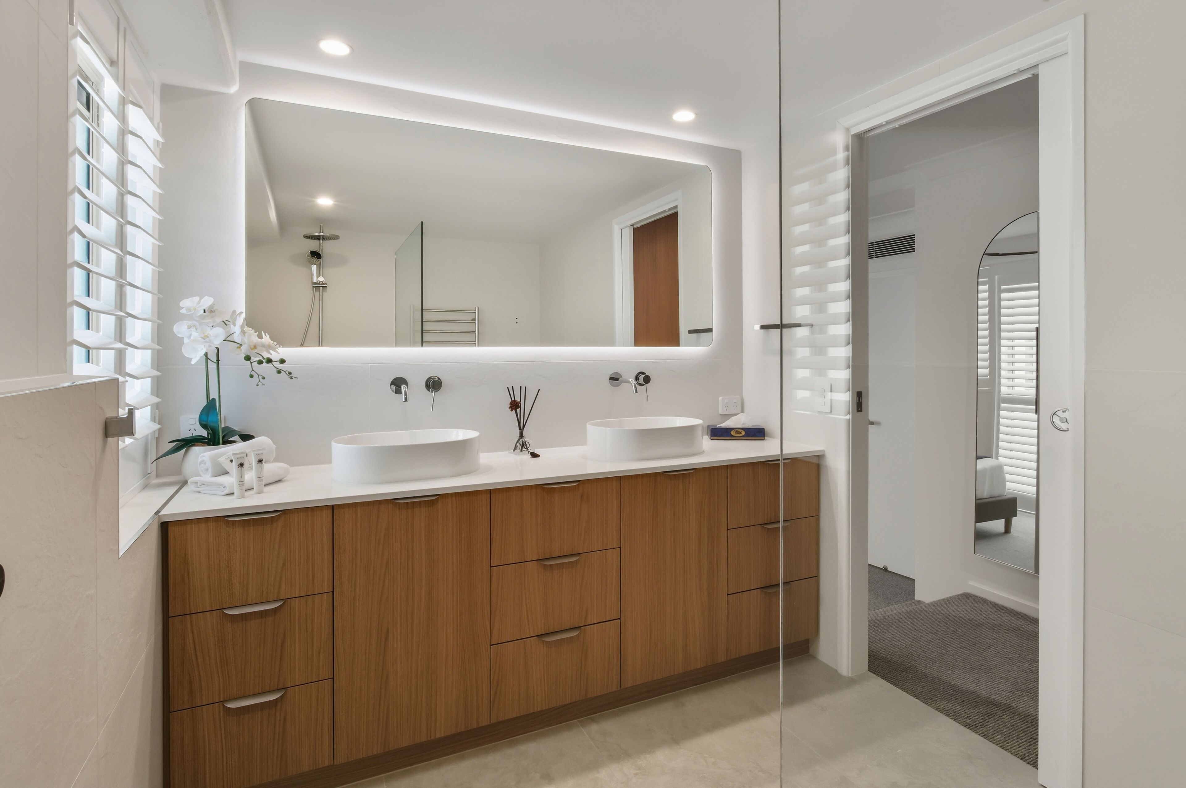 Un baño moderno con dos lavamanos, muebles de madera y un espejo grande.