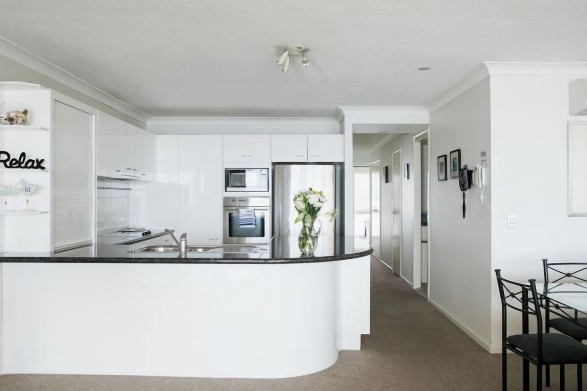 A modern kitchen with white cabinets, a black countertop, and a central island.