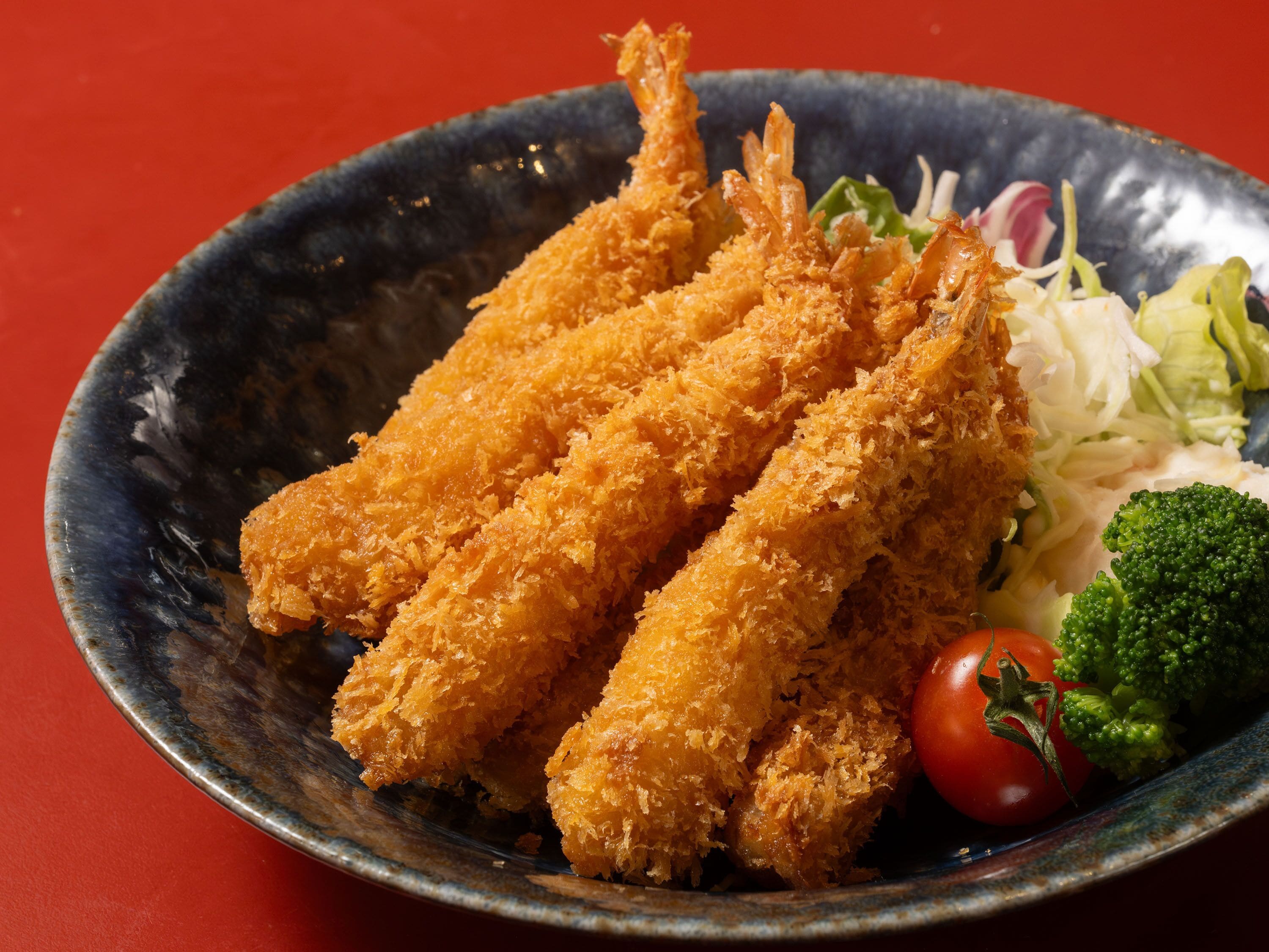 A plate with breaded food items, vegetables, and a red background.