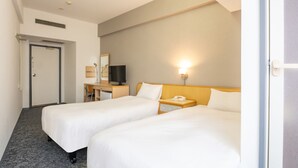 Habitación de hotel con dos camas, un escritorio con televisor, una lámpara de noche y un teléfono.