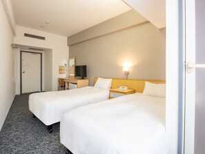 A hotel room with two beds, a desk with a TV, a bedside lamp, and a phone.