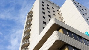 Un hotel moderno con un llamativo letrero 'CHIJN', varios pisos y un balcón en el lado izquierdo.