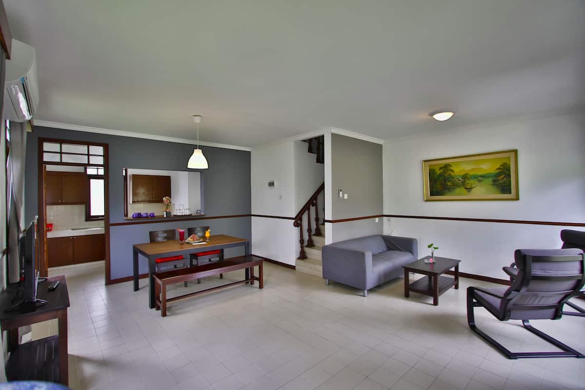 A spacious living area with a dining table, sofa, and a staircase leading to another level.