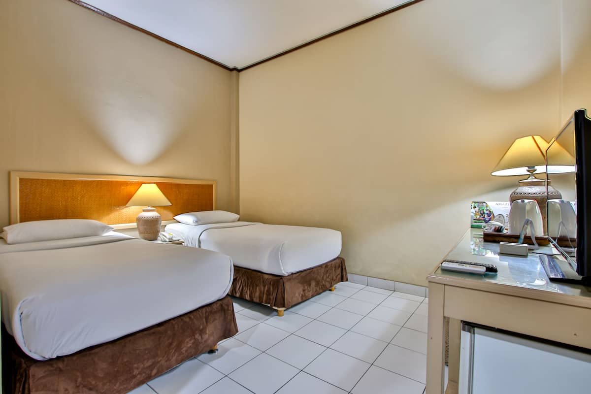 Una habitación de hotel con dos camas, un escritorio con lámpara y televisión.