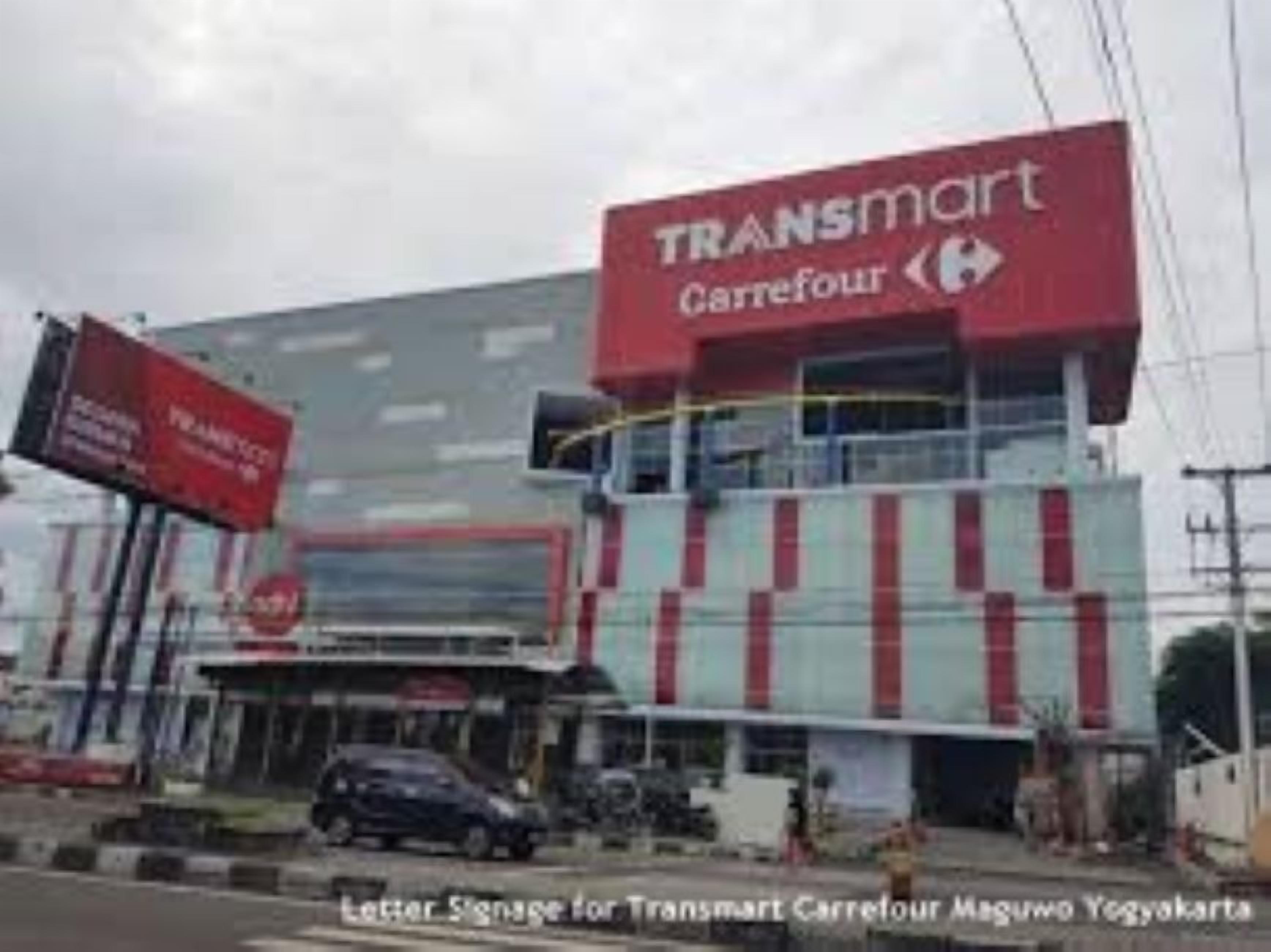 A Transmart Carrefour building with a large sign, a visible entrance, and a parking area.