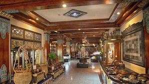 A traditional interior with wooden beams, ornate decorations, and a variety of pottery and baskets displayed along the walls.