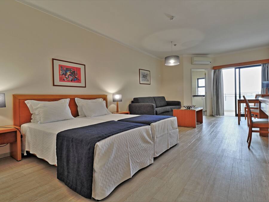 Ein Hotelzimmer mit einem Bett, einer Couch, einem Schreibtisch und einem Sessel.