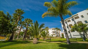 A hotel with multiple floors, palm trees, and a well-maintained lawn.