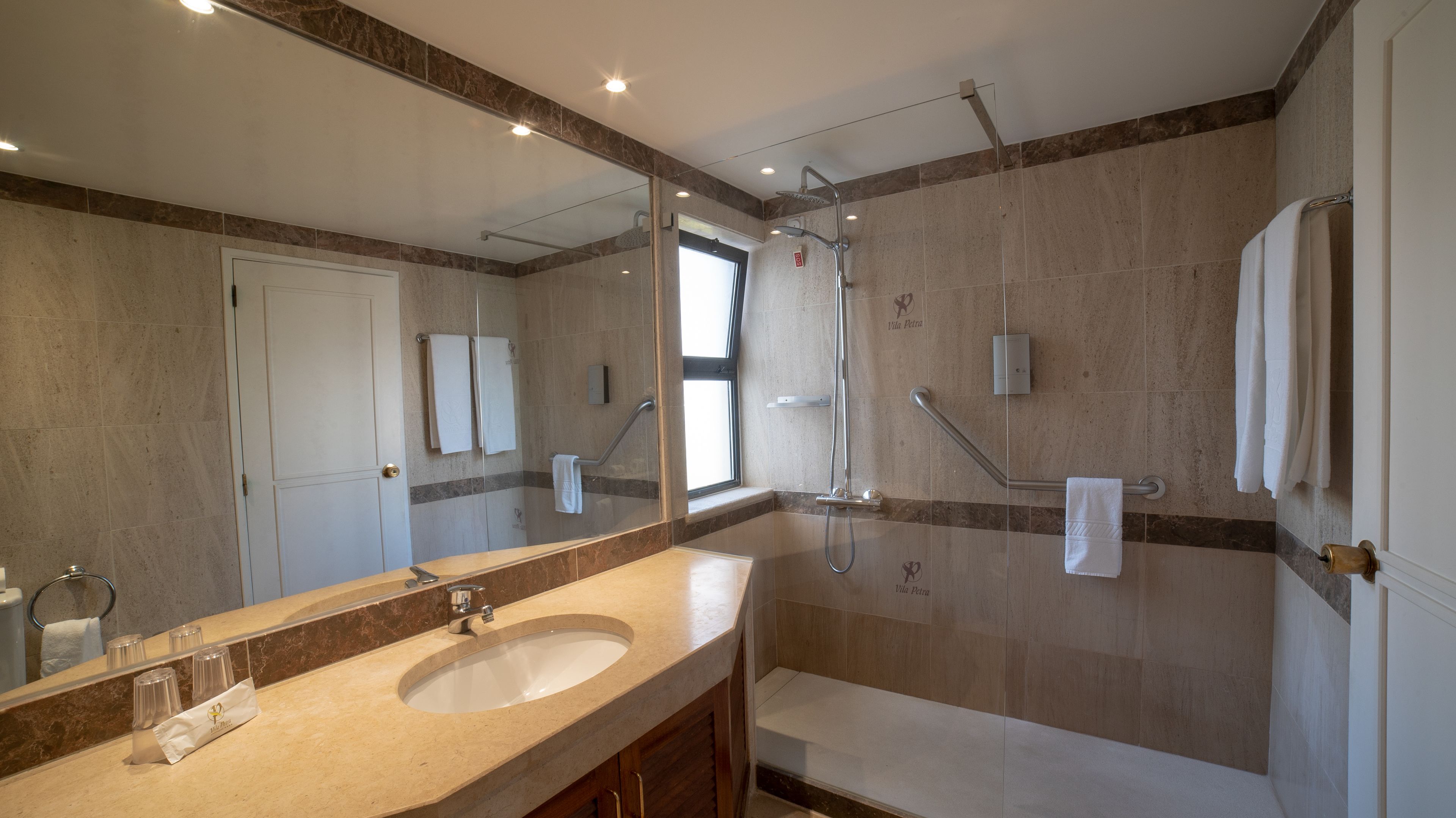 Un baño moderno con un espejo grande, un lavabo, una ducha y un inodoro.