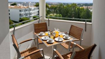 Un balcon avec une table mise pour le petit-déjeuner, comprenant des assiettes, des tasses et du jus d’orange.