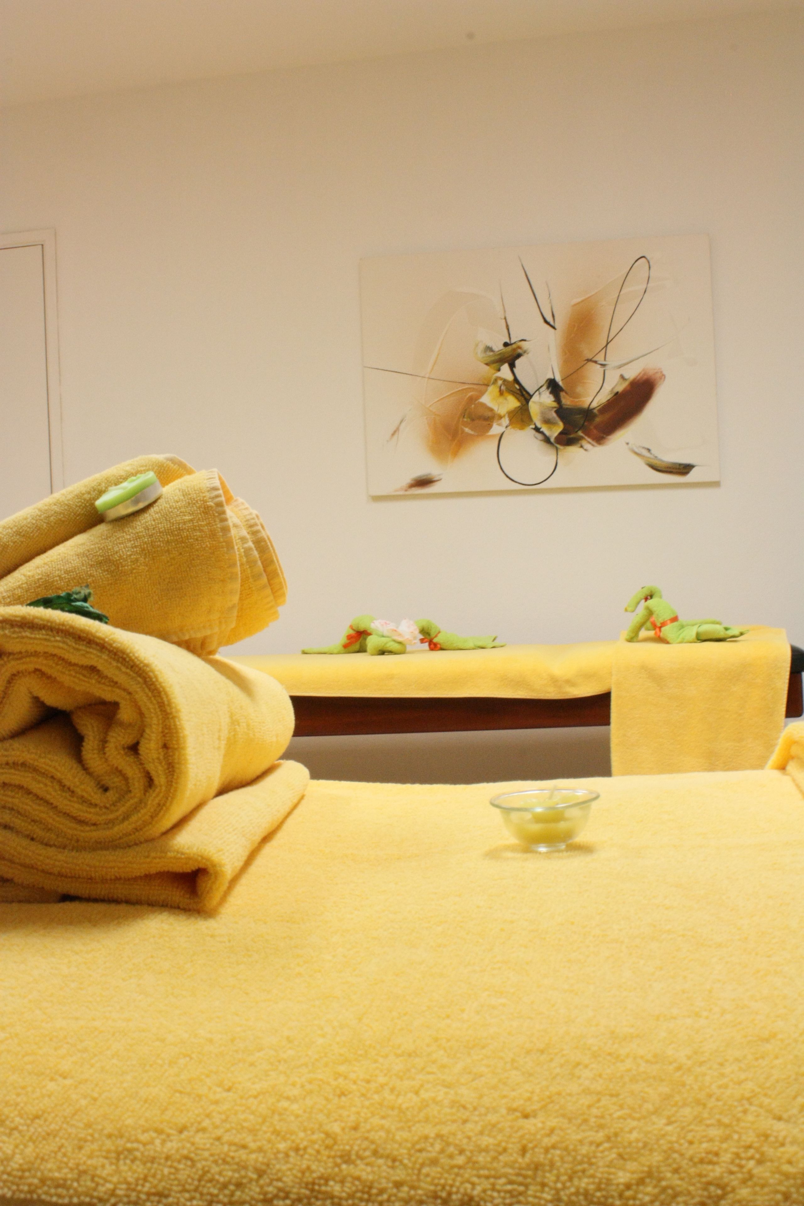 Een wellnessruimte met een massagetafel, handdoeken en een decoratief object aan de muur.