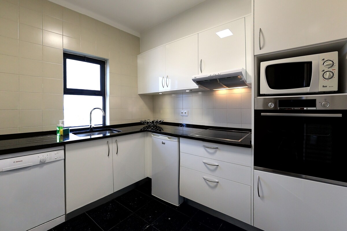 A modern kitchen with white cabinets, a Bosch dishwasher, a microwave, and a stove.