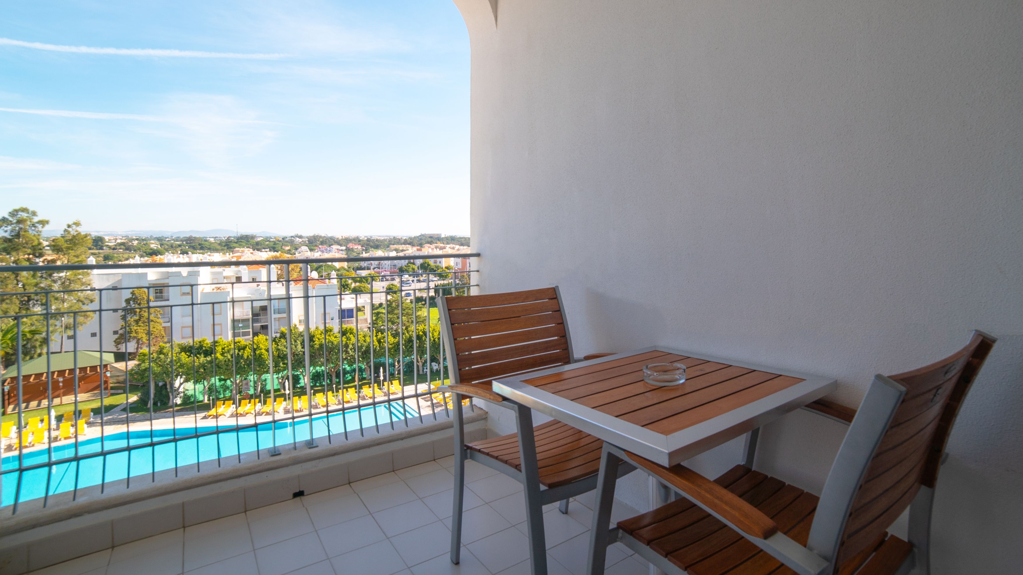 A balcony with a view of a swimming pool and buildings.