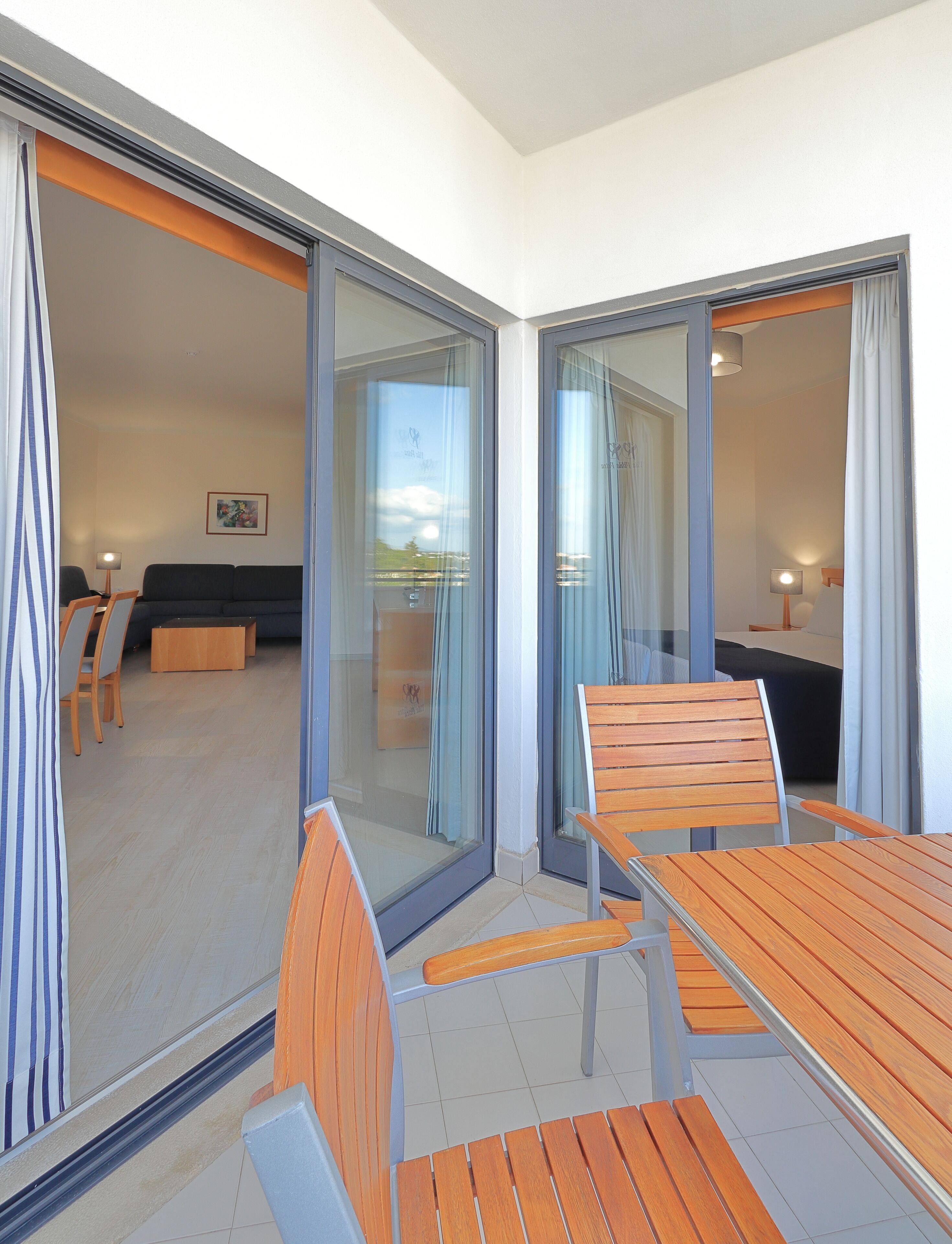 Una habitación de hotel moderna con balcón, un sofá, una mesa de comedor y una silla.