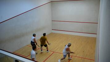 A squash court with wooden flooring and red boundary lines.