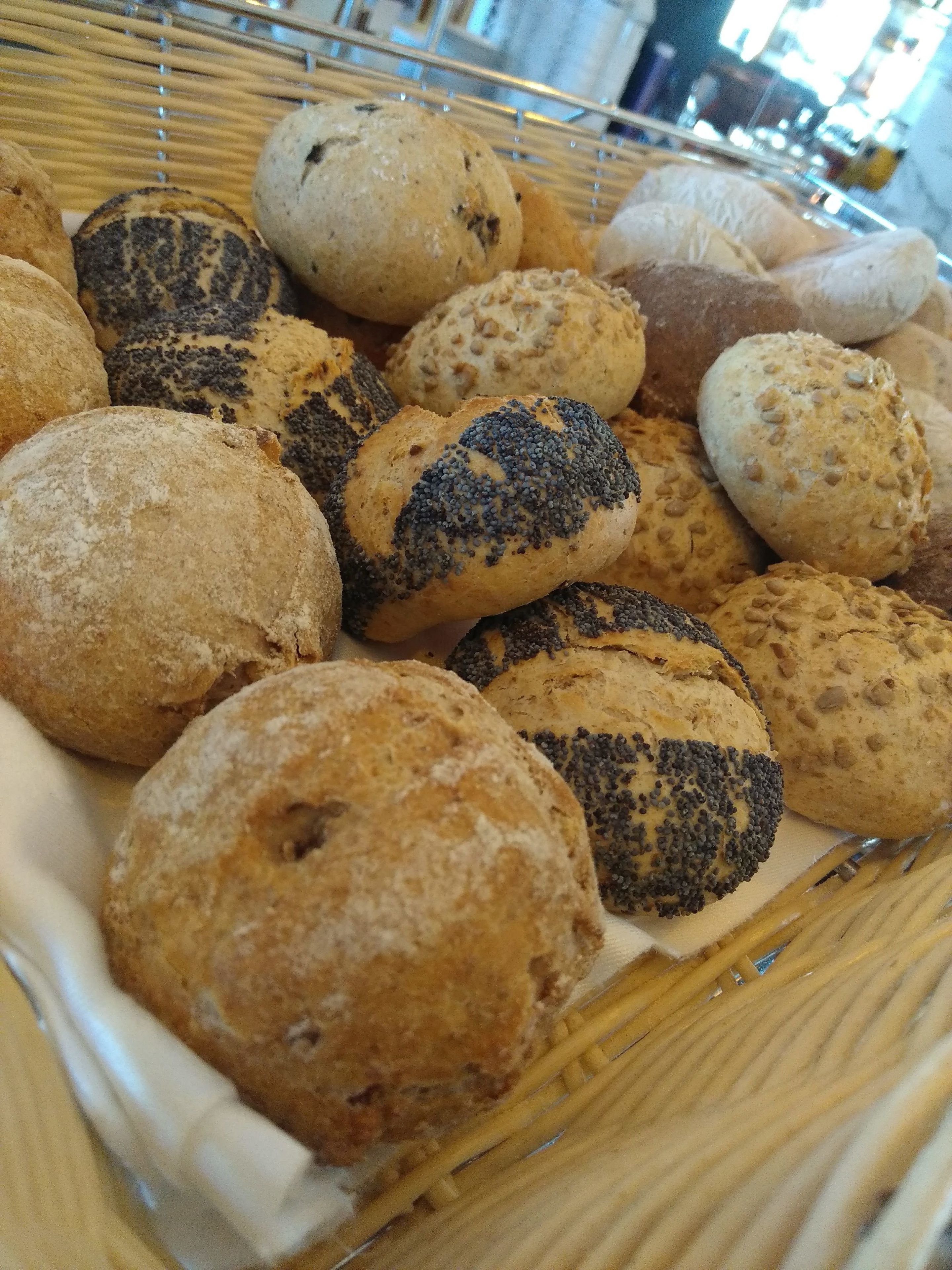 A basket of various breads, including poppy seed and sesame seed varieties.