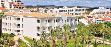 A hotel with multiple white buildings, palm trees, and a clear sky.