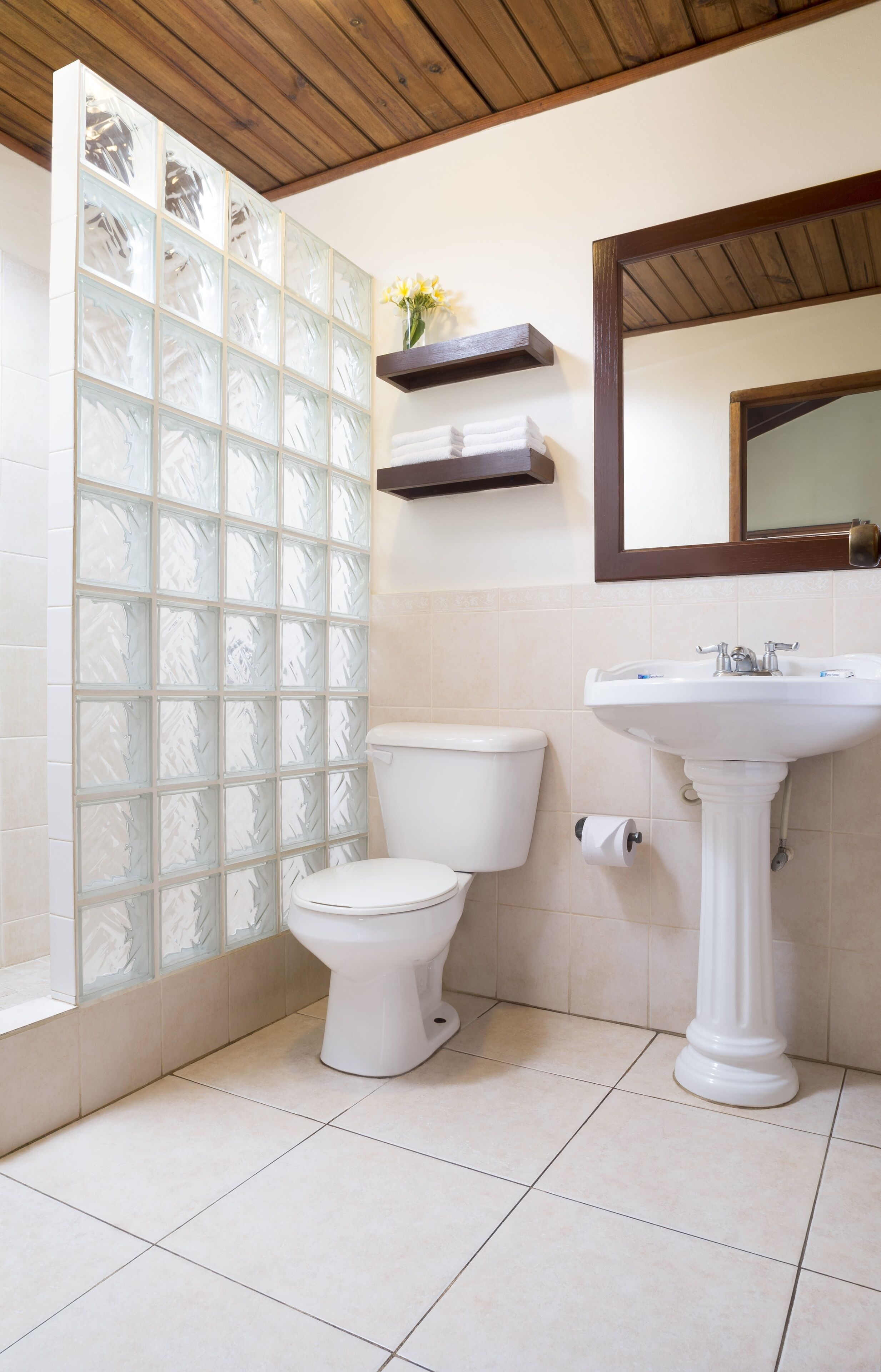Un baño con inodoro, lavamanos y mampara de vidrio esmerilado.