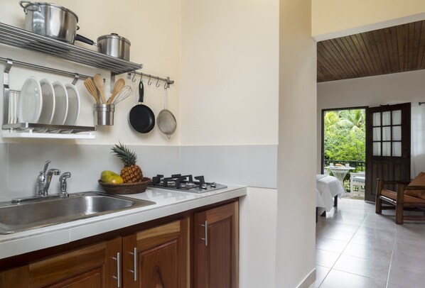A kitchen with stainless steel appliances, wooden cabinets, and a dining area with a view of greenery. - White Sands Negril (Negril)