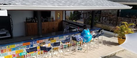 Uma área de bar com piso ladrilhado e um balcão exibindo várias placas de licença.