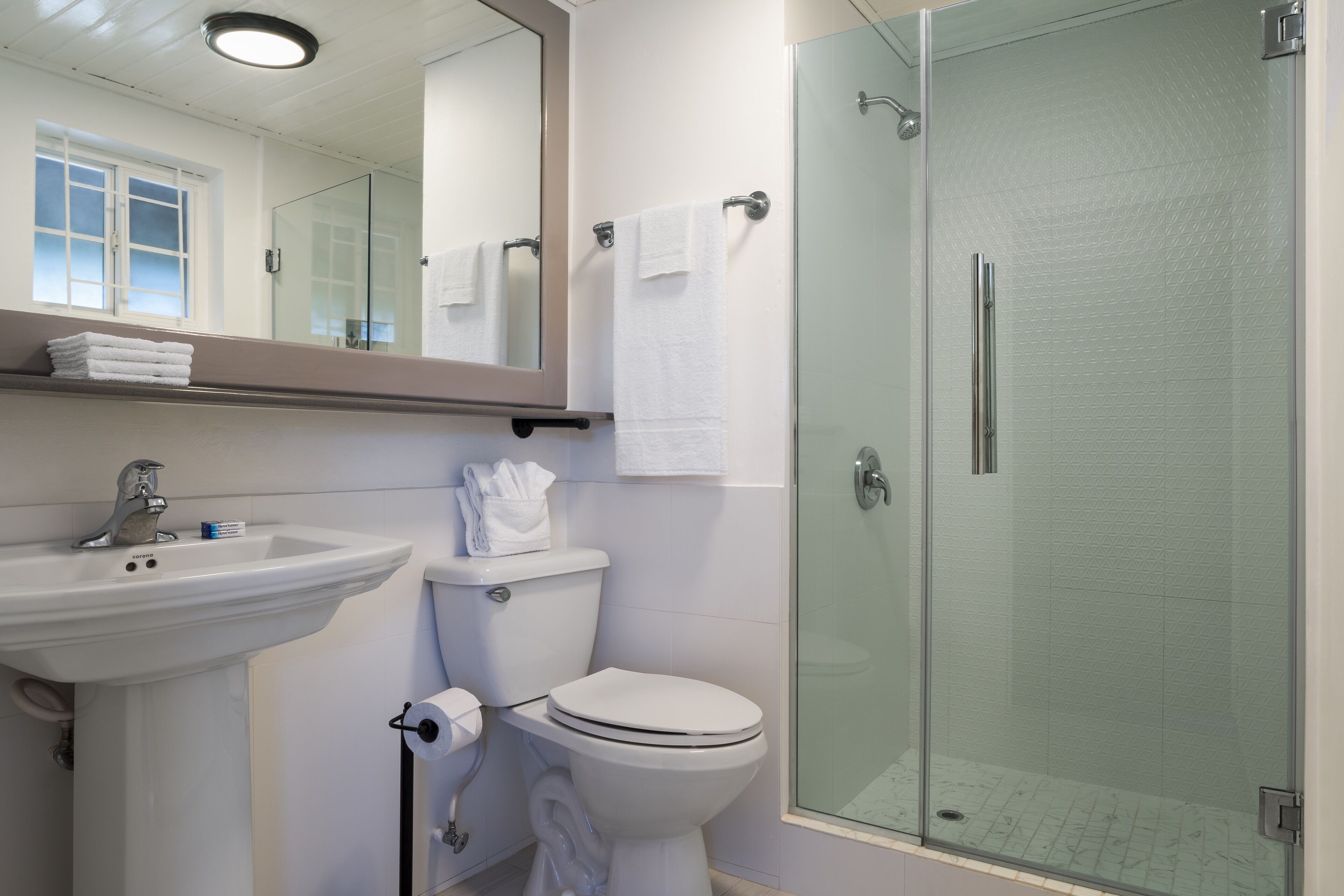 Un baño moderno con lavamanos, inodoro y ducha con mampara de vidrio.