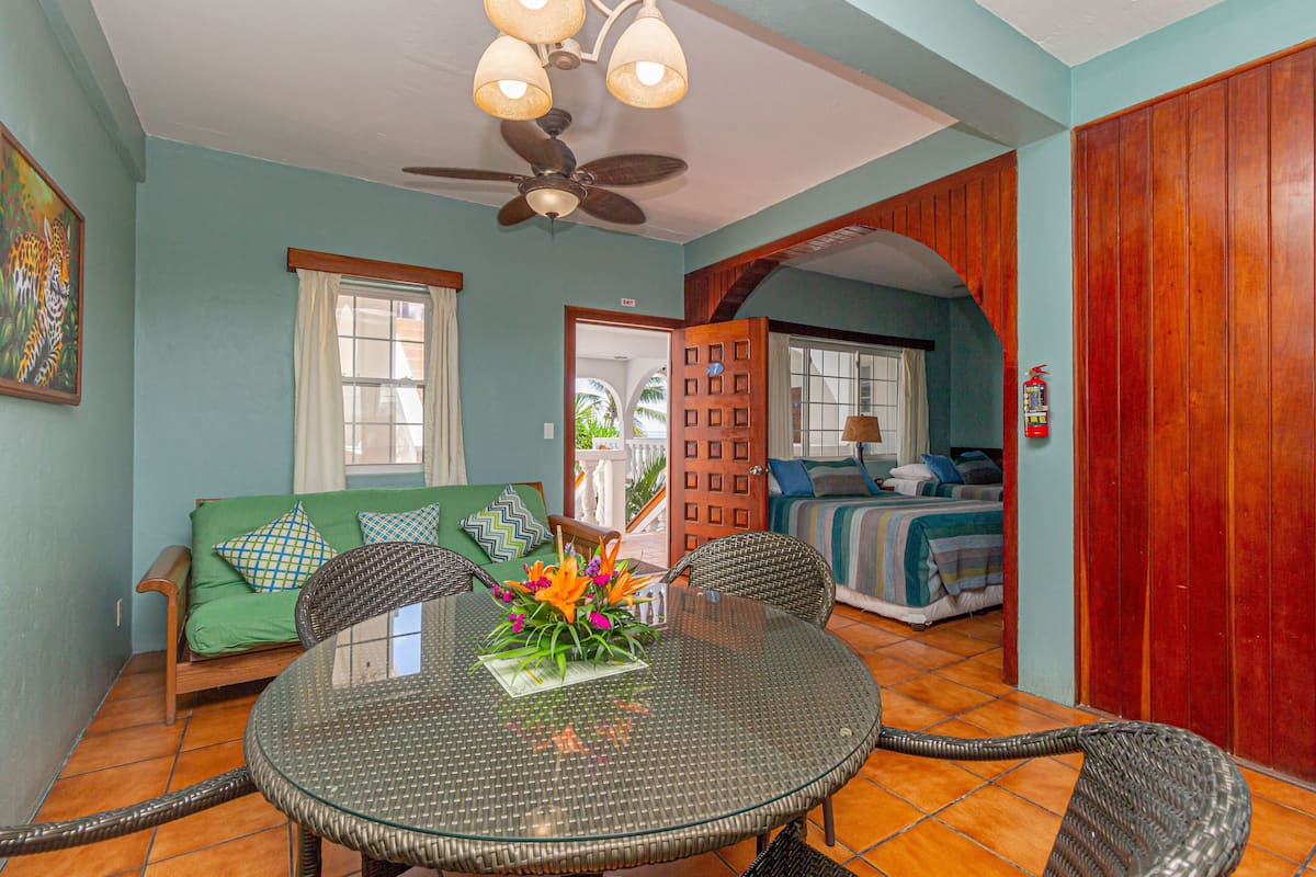 A dining area with a round glass table, wicker chairs, and a ceiling fan.