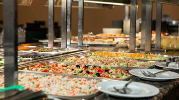Un bufé con diversas opciones de comida, incluyendo ensaladas, platos de arroz y carnes.