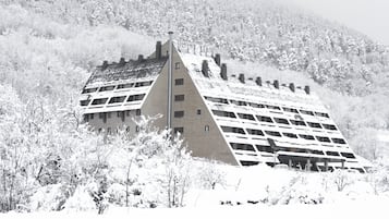 Un hotel con una estructura de techo triangular distintiva, rodeado de árboles cubiertos de nieve.