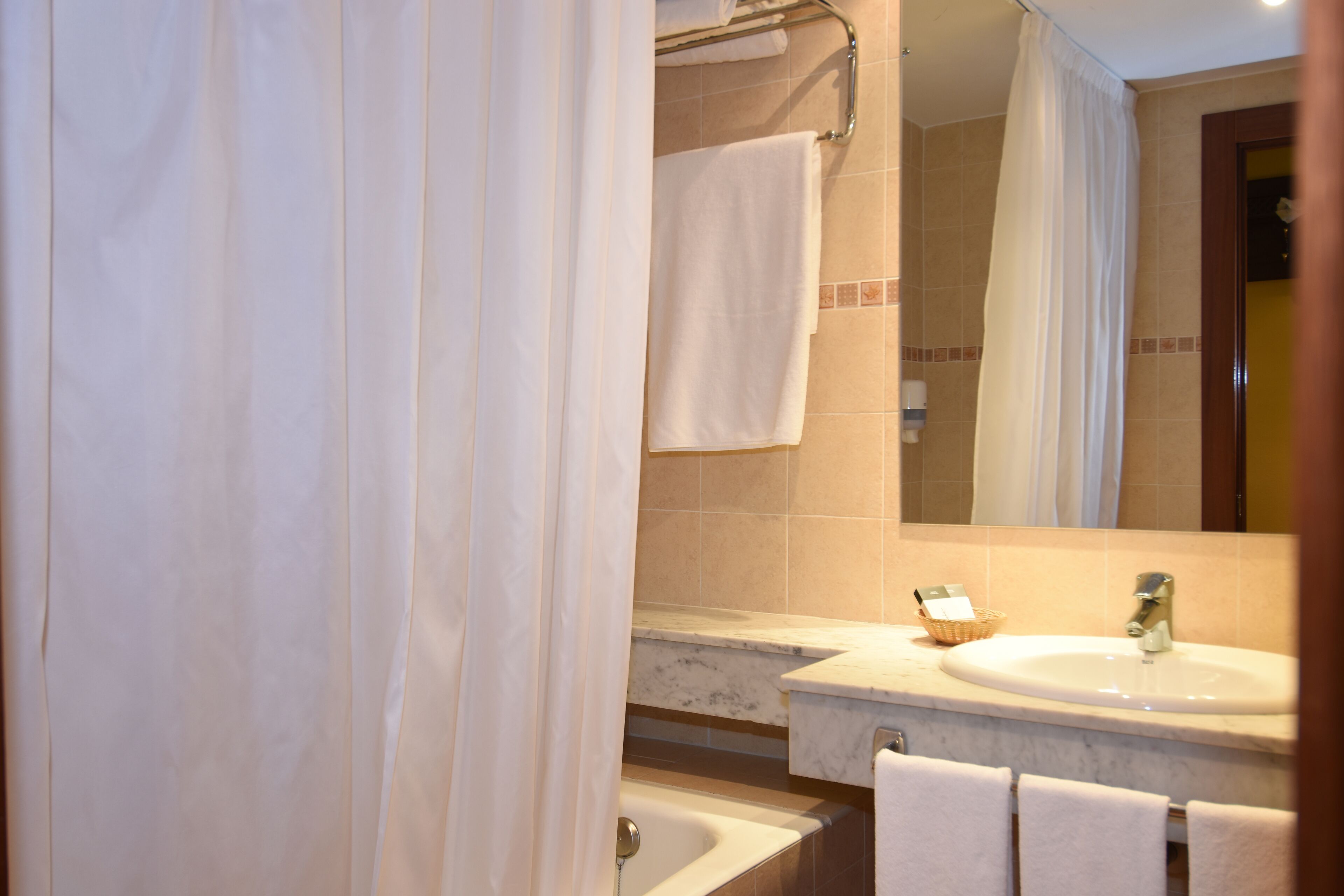 A bathroom with a sink, mirror, towel rack, and shower curtain.