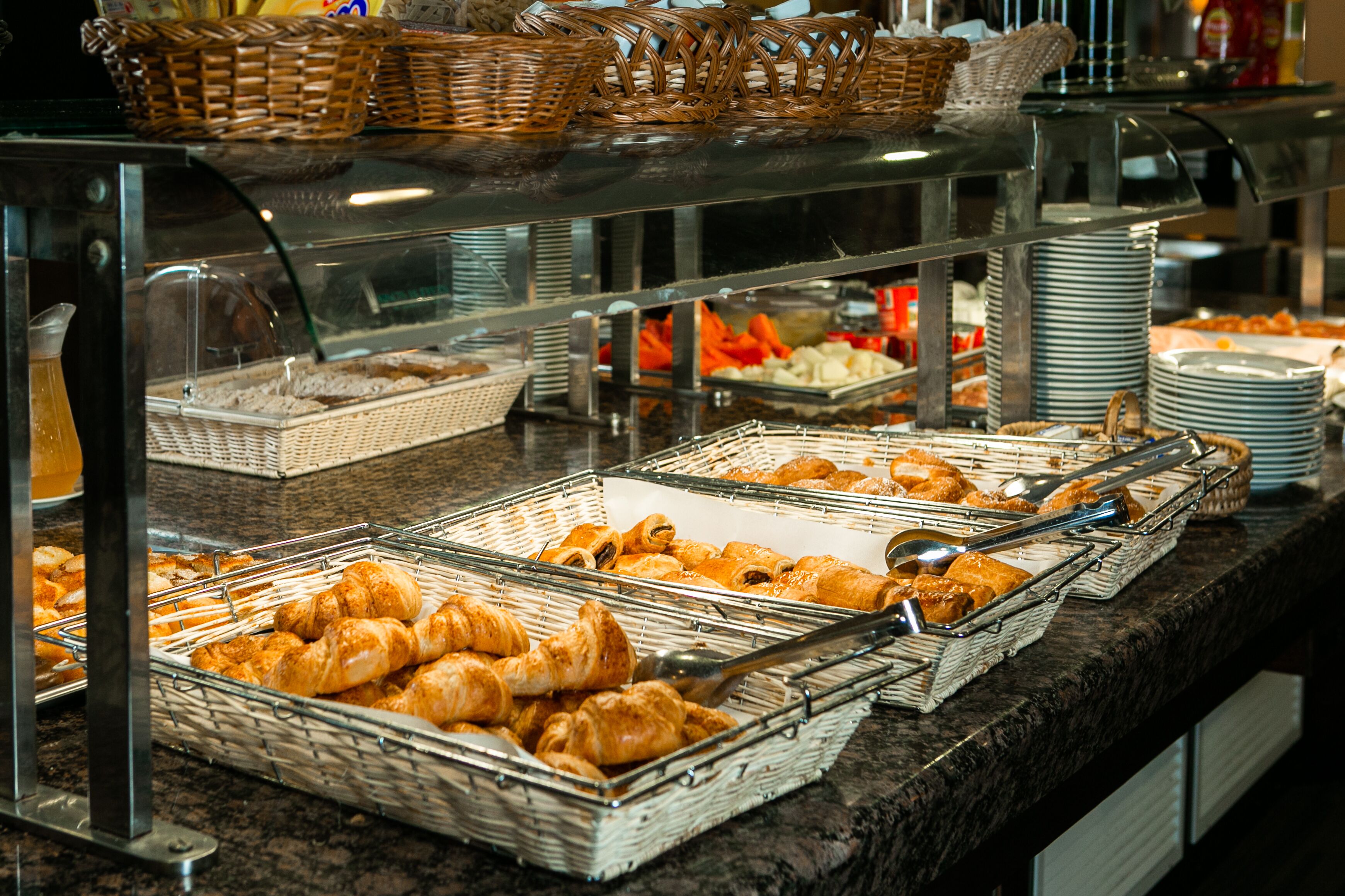 Un buffet proposant une variété de plats, notamment des pâtisseries et des fruits, présentés dans des paniers et sur des plateaux.