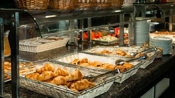 Un buffet proposant une variété de plats, notamment des pâtisseries et des fruits, présentés dans des paniers et sur des plateaux.
