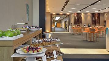 A buffet with various food items and a seating area with tables and chairs.