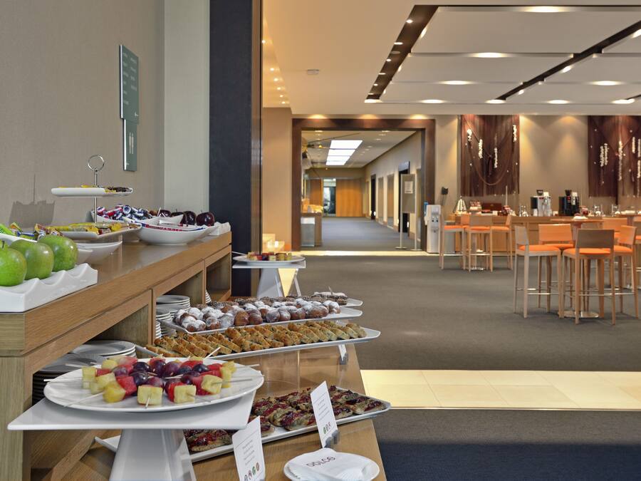 A buffet with various food items and a seating area with tables and chairs.