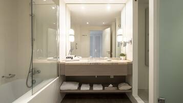 A modern bathroom with a glass-enclosed shower, a large mirror, and a vanity with a sink and towel storage.