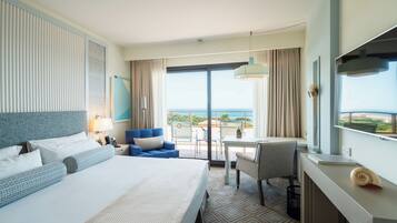 Ein Hotelzimmer mit einem großen Bett, einem Schreibtisch, einem Sessel und Meerblick.