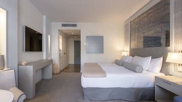 A modern hotel room with a large bed, bedside tables, a desk, and a television.