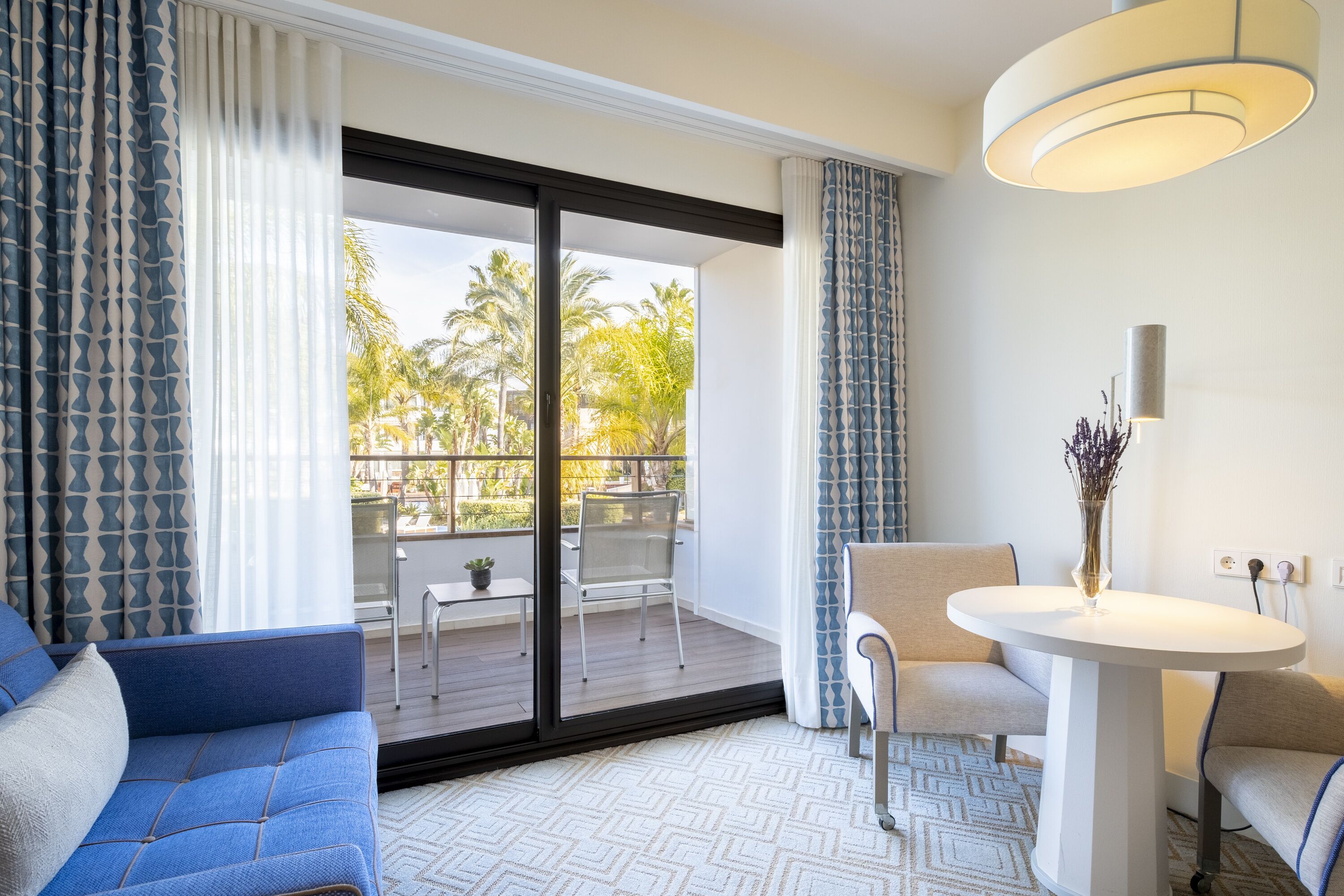 A modern room with a sofa, a small table, a chair, and a view of the outdoors.
