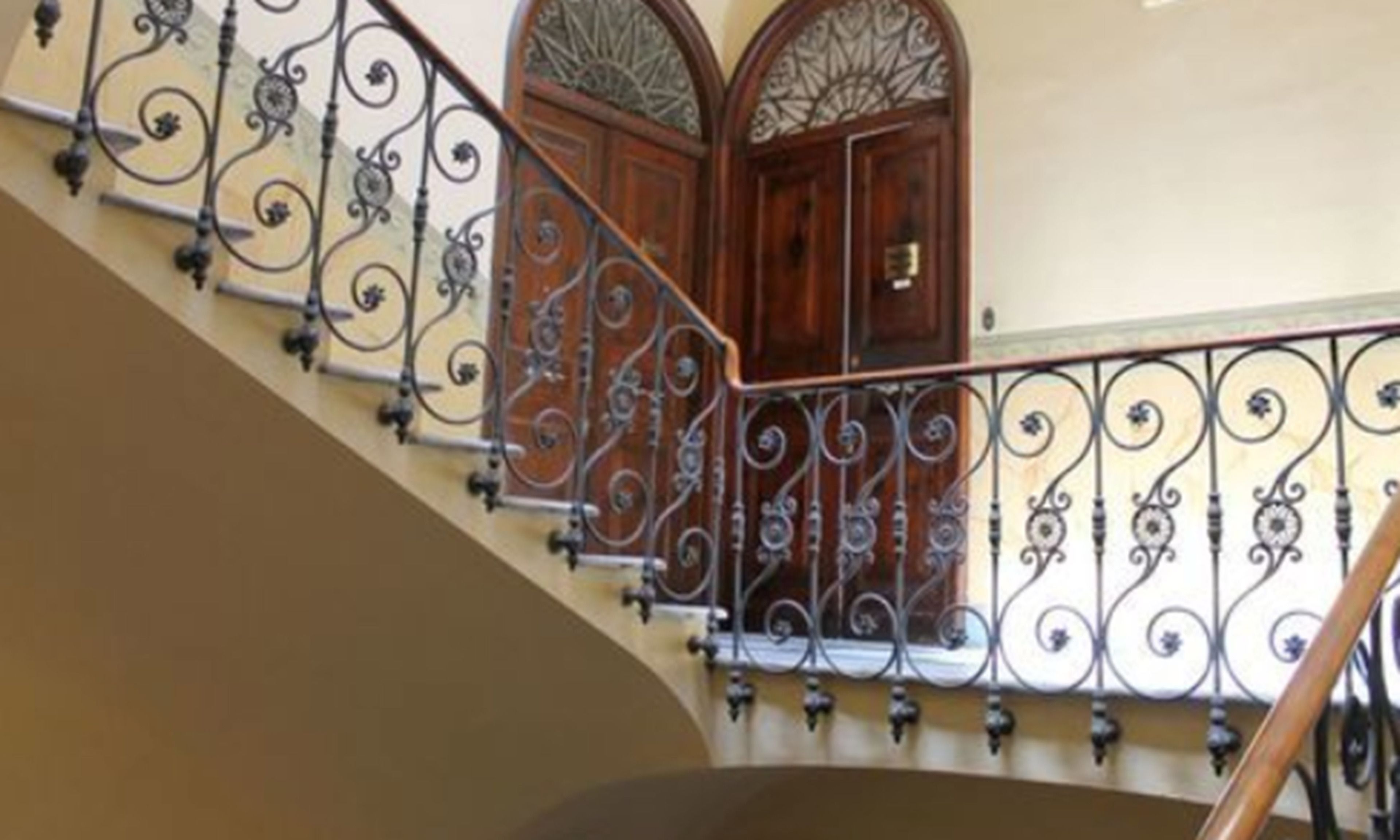 Una scala con ringhiere in metallo elaborate e porte in legno con pannelli di vetro decorativi.