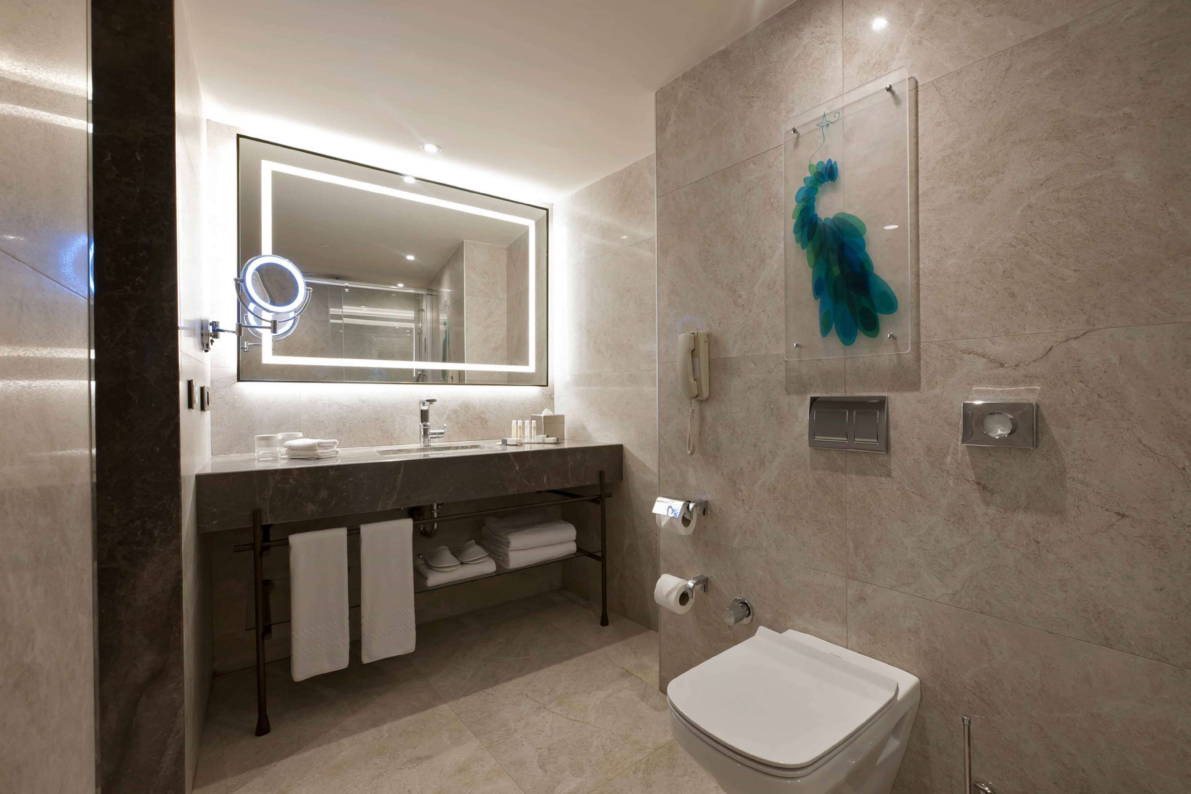 Une salle de bain moderne avec un grand miroir, un meuble-lavabo et des toilettes.