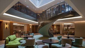 A modern hotel lobby with a spiral staircase, multiple seating areas, and a dining space. - DoubleTree by Hilton Hotel Istanbul - Sirkeci (Istanbul)