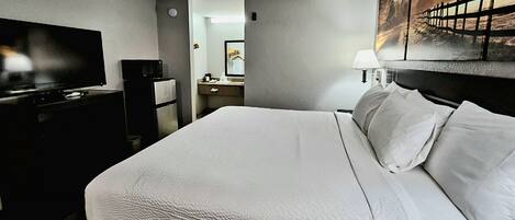 Habitación de hotel con una cama grande, un televisor de pantalla plana, un escritorio y un cuadro en la pared.