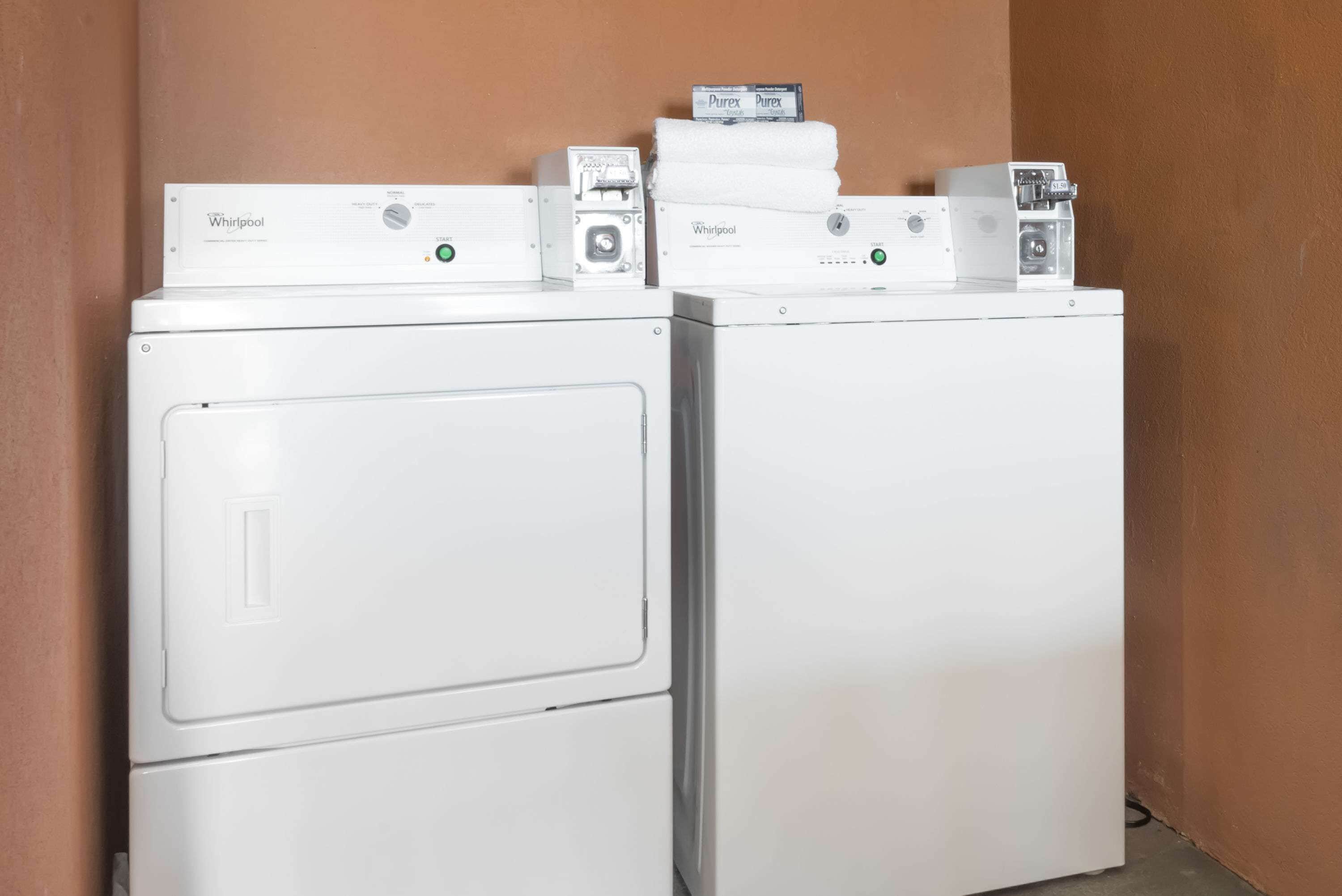 Two stacked Whirlpool washing machines in a corner with a brown wall.