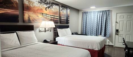 A hotel room with two beds, a desk, a chair, a lamp, and a window with curtains.