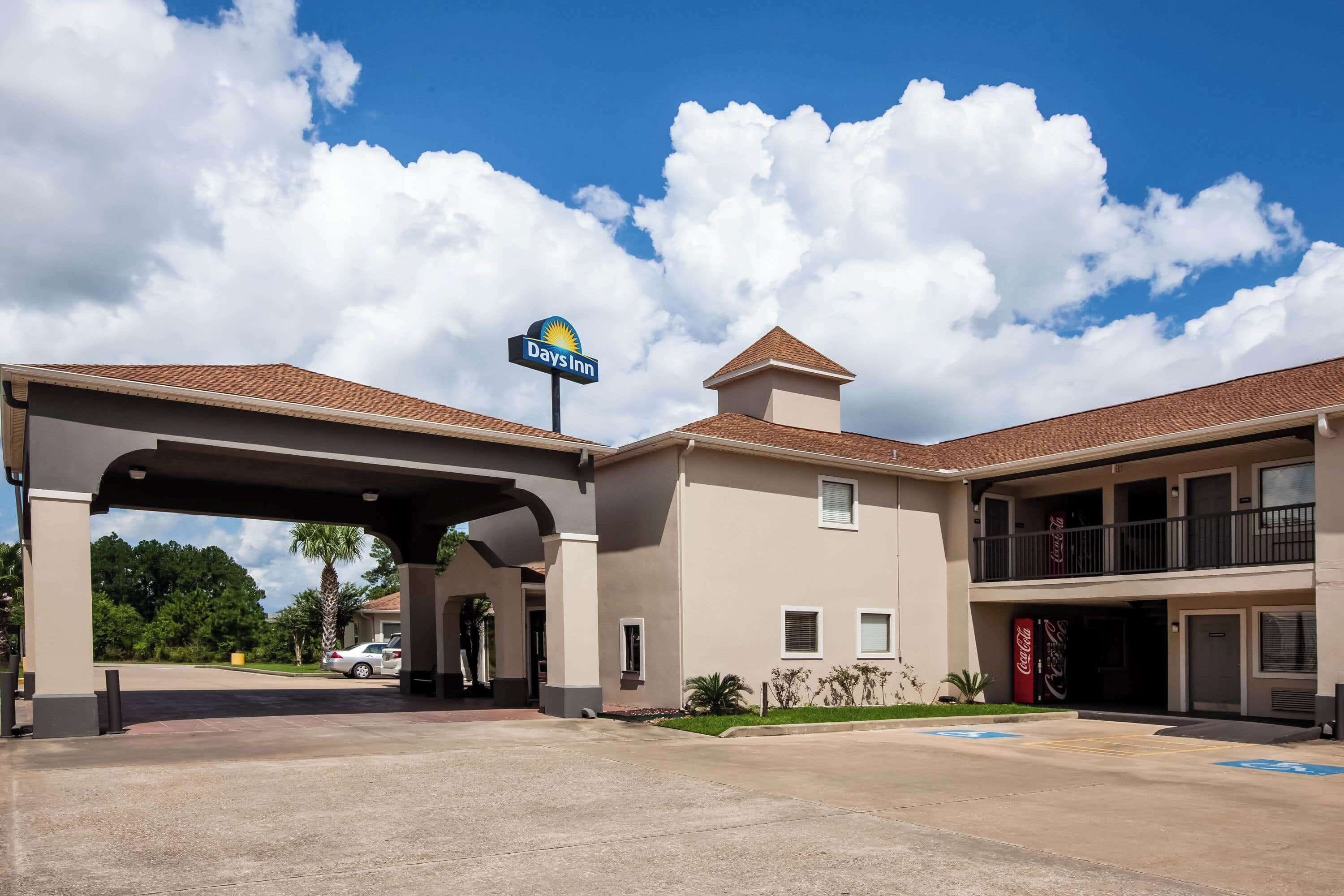 Ein Days Inn Hotel bei blauem Himmel mit Wolken, einem Parkplatz und einem Coca-Cola Schild.
