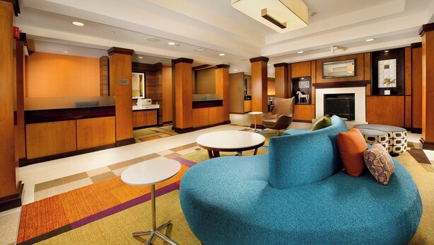 A modern lobby with a blue sofa, a fireplace, and a reception desk. - Fairfield Inn & Suites Germantown Gaithersburg (Germantown)