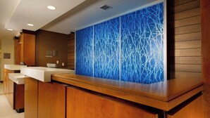 A reception area with a wooden reception desk, a blue abstract wall, and a sign indicating a non-smoking area. - Fairfield Inn & Suites Germantown Gaithersburg (Germantown)