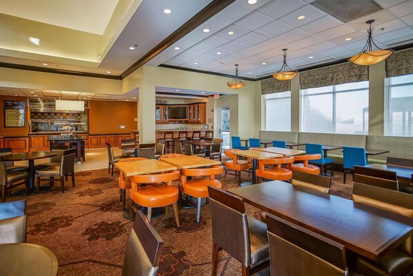 A restaurant with a central bar area, multiple dining tables, and chairs.