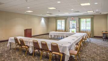 A conference room with long tables and chairs, a podium, and a door marked "EXIT".